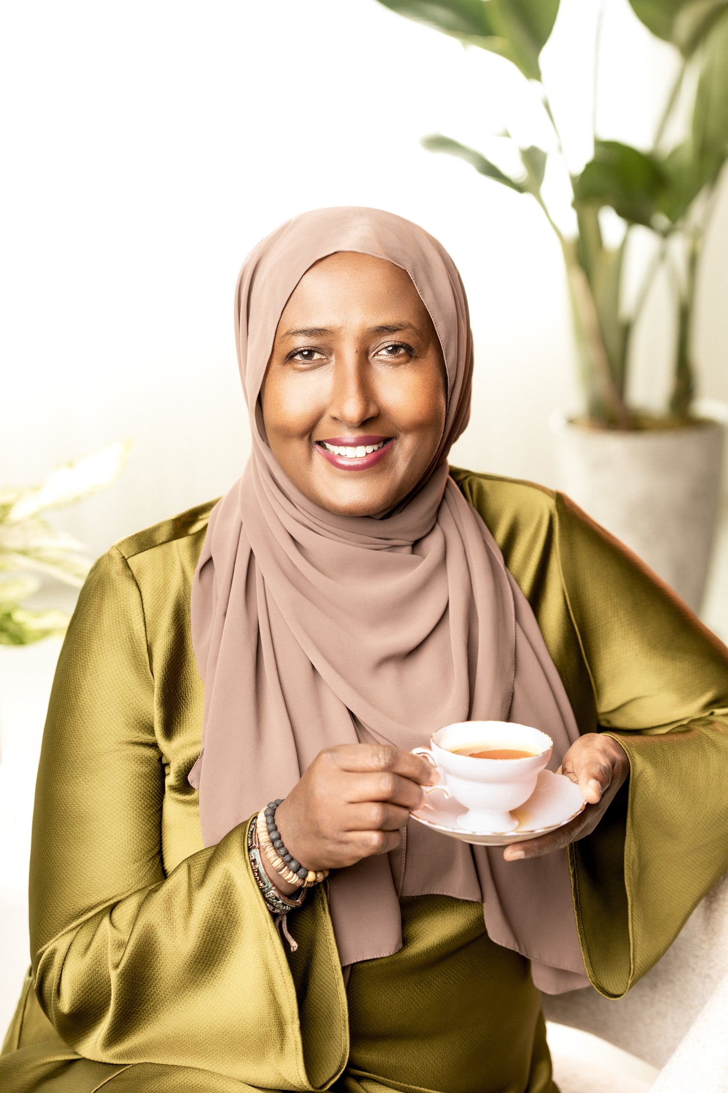 Osobelle Tea Founder holding a cup of tea with plants in the background